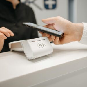 Person using a smartphone for contactless payment at a retail counter, highlighting cashless convenience.