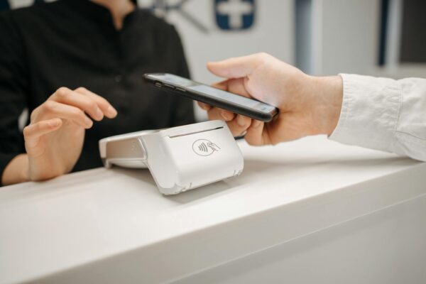 Person using a smartphone for contactless payment at a retail counter, highlighting cashless convenience.